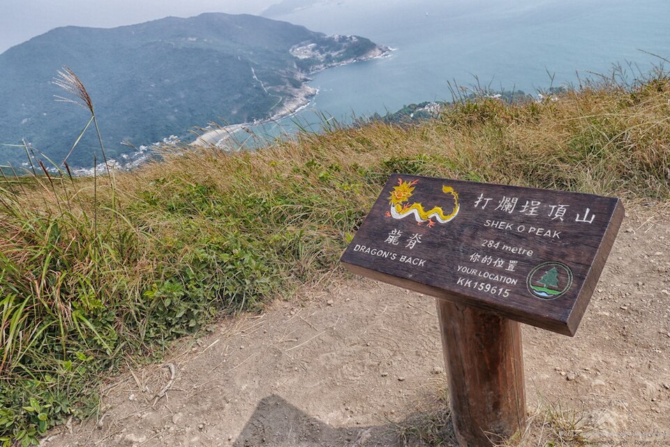 石澳ピークの山頂標識と背後の海岸