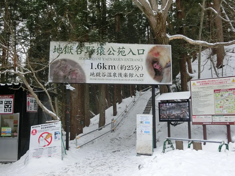 雪が残る地獄谷入口の標識と階段