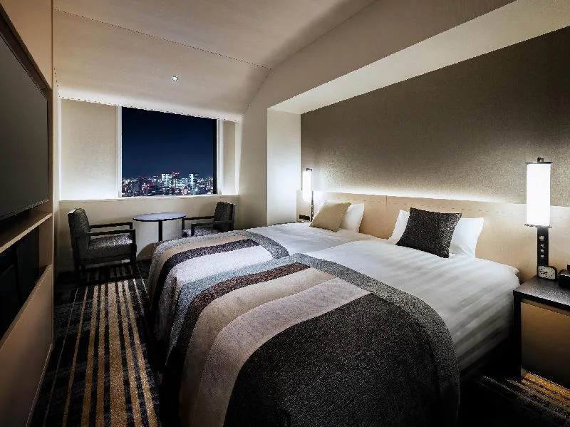 Dvě postele a posezení u okna v hotelu Hankyu RESPIRE Osaka
