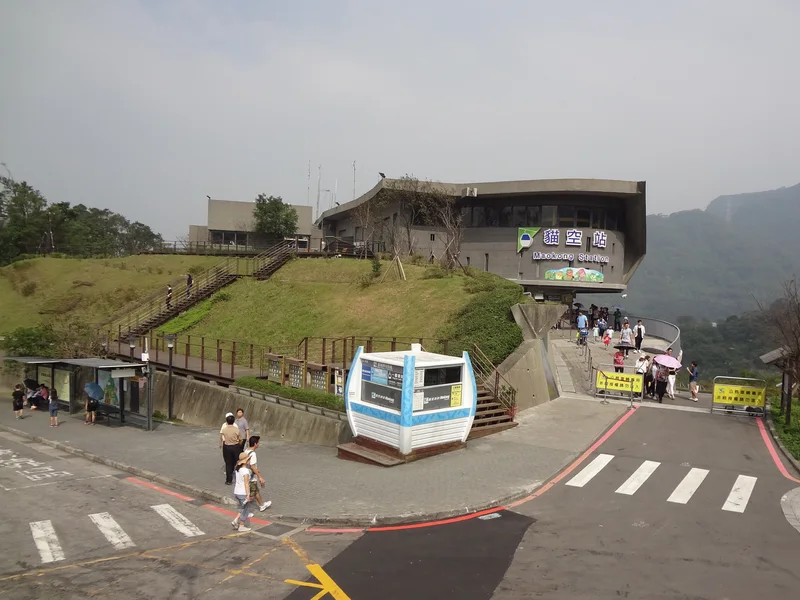 丘の上にある猫空駅の建物と駅前の道路・歩道