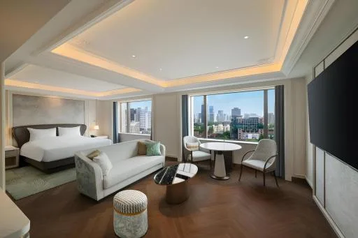 Postel a pracovní stůl u okna v Okura Garden Hotel Shanghai