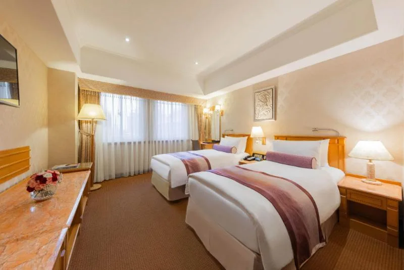 Hai giường và cửa sổ trong phòng Cosmos Hotel Taipei