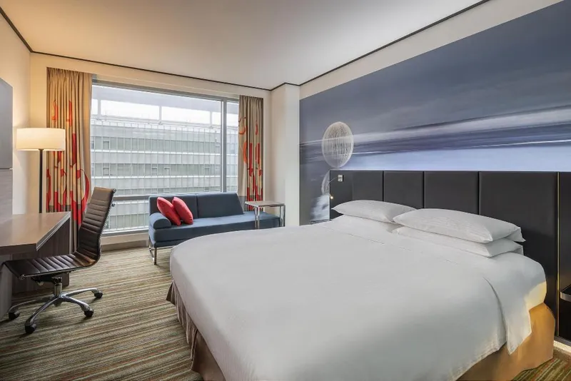 Giường và ghế cạnh cửa sổ trong phòng Deluxe King tại Hyatt Regency Taoyuan