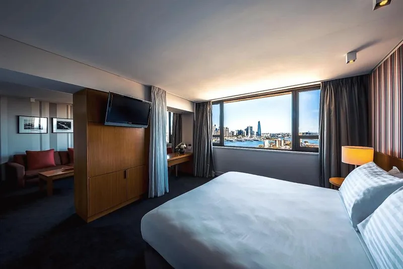 View Sydneyの客室のベッドと窓外の港の風景