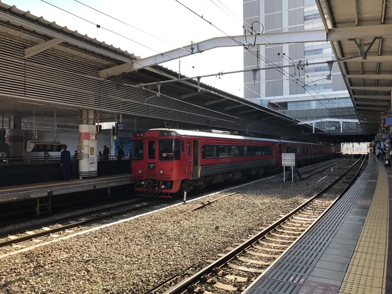 Červený expres Yufu stojí u nástupiště stanice Hakata